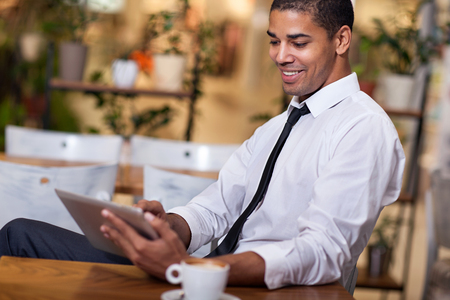 smiling businessman in the restaurant  working on touchpadの写真素材