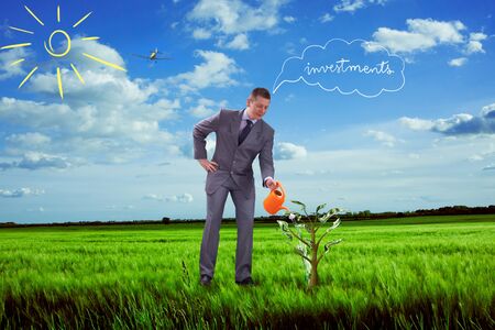 businessman watering tree with money and waiting to grow investmentsの写真素材