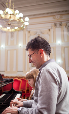 father teaches young daughter playing pianoの写真素材