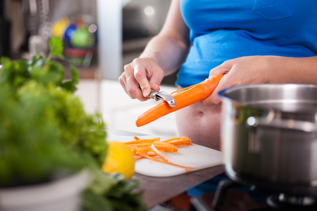Pregnant woman preparing a healthy meal in the kitchenの写真素材
