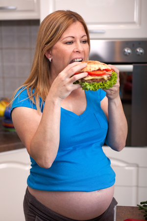 pregnant woman with an appetite eating hamburgerの写真素材