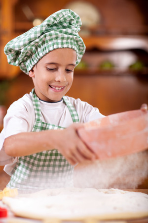 happy smiling young boy chef in kitchenの写真素材