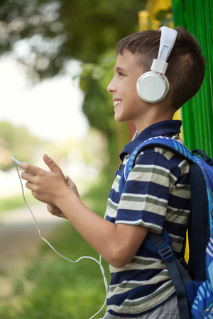 little boy goes to school and listen to music via smartphoneの写真素材