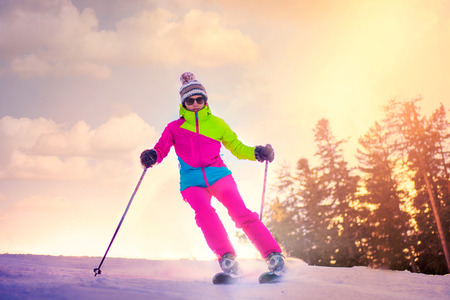 woman skiing downhill in sunsetの写真素材