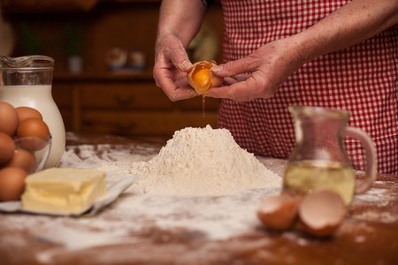 Senior woman hands preparing flour and eggs for cakes or breadの写真素材