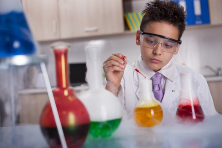 little schoolboy working in chemistry labの写真素材