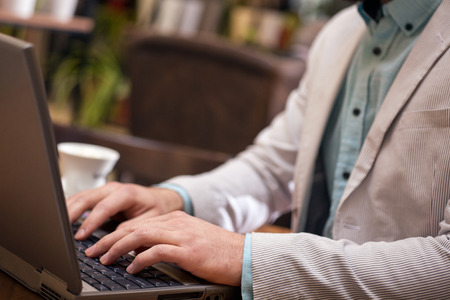 close up hands of businessman working on lap top in restaurant on coffee breakの写真素材