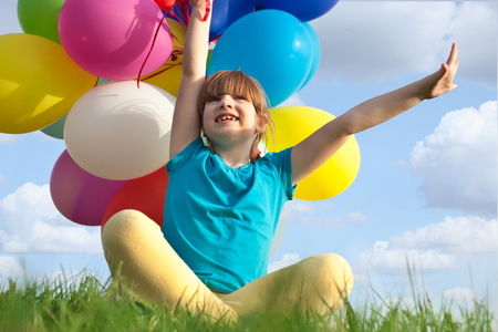 Kid having fun in spring field against blue sky backgroundの写真素材