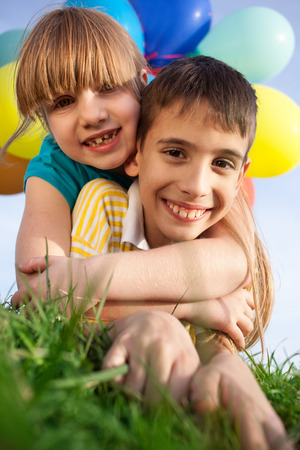 Happy smiling kids  with balloons on a green meadowの写真素材