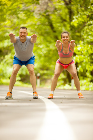 fitness, sport, friendship and lifestyle concept - smiling couple execirse in green forestの写真素材