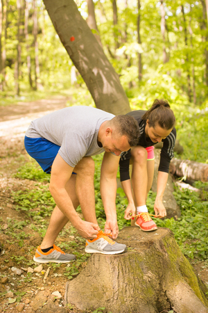 man and woman tying sport shoes ready for run in forrestの写真素材