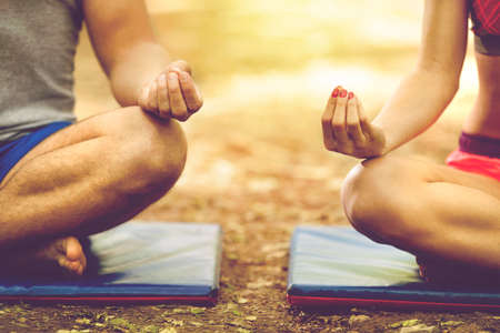 Young man and woman doing yoga in the sunny summer parkの写真素材