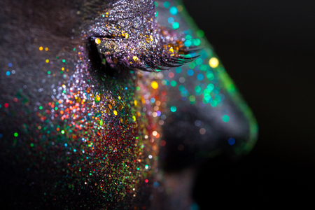 Portrait of beautiful woman with sparkles on her face. Fashion model with colorful make-upの写真素材