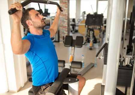 Sport, fitness, lifestyle, technology and people concept. Young man training in the gym