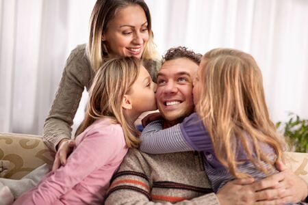 daughters kissing her dad,happy mom looking and smilingの写真素材