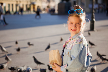 modern young girl feeding pigeons on the city squareの写真素材