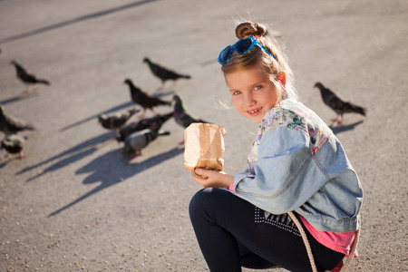 modern young girl feeding pigeons on the city squareの写真素材