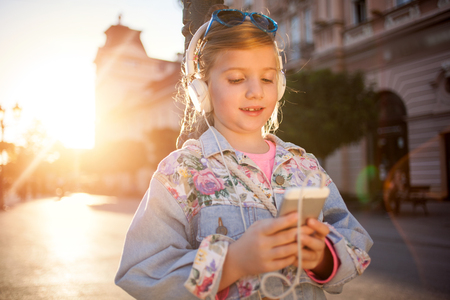 Pretty  young girl listening music with her headphones in the streetの写真素材