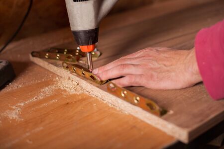 Carpenter drilling wooden board in workshopの写真素材