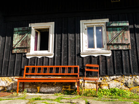 Brown bench at doorstep of wooden cottageの写真素材