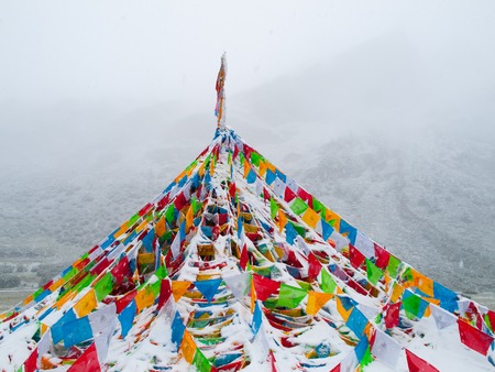 Buddhist tibetan prayer flags in snowy and foggy weatherの写真素材