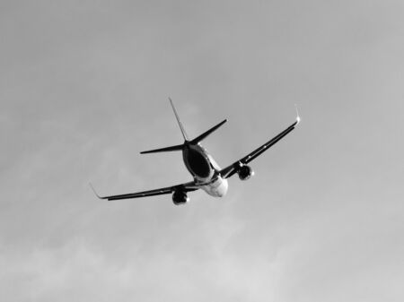 Silhouette of aircraft flying in the sky, backside view, black and white imageの写真素材