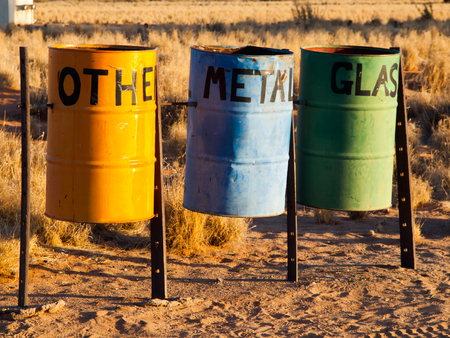 Three colorful recycle bins for metal, glass and other waste in the nature. Tin Barrels on at the camping site for waste separation.の写真素材