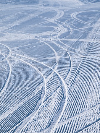 Empty morning ski slope groomed with several tracks from skiersの写真素材