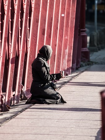 Muslim woman in black clothes sitting on the street and asking for alms.の写真素材