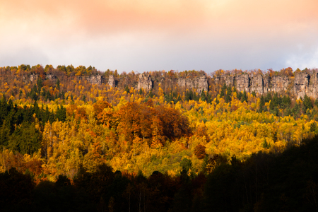 Panoramic view of sandstone rock formation in the middle of colorful autumn forest. Dramatic evening view. Tisa Rocks, aka Tiske Walls, Czech-Saxon Switzerland, Czech Republicの写真素材