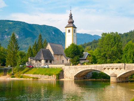 Church of St John the Baptist and old stone bridge at Lake Bohinj in alpine village Ribicev Laz, Julian Alps, Slovenia.の写真素材