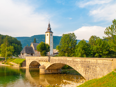Church of St John the Baptist and old stone bridge at Lake Bohinj in alpine village Ribicev Laz, Julian Alps, Slovenia.の写真素材