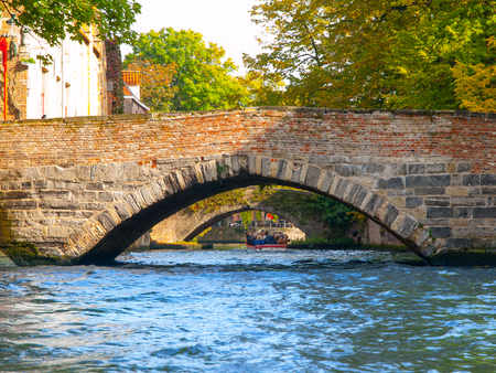 Town water canals with tourist boats in the historical center of Bruges, aka Brugge, Belgium, Europe.の写真素材