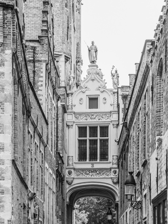 Bridge crossing between buildings over narrow Blinde-Ezelstraat, aka Blind donkey street, near Burg square, Bruges, Belgium. Black and white image.の写真素材