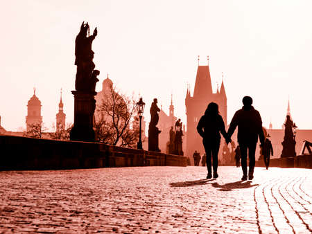 Foggy morning on Charles Bridge, Prague, Czech Republic. Sunrise with silhouettes of walking people, statues and Old Town towers. Romantic travel destionation.の写真素材
