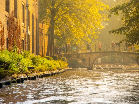 Old brick houses along water canals and old stone bridge in Bruges, Belgium.の写真素材