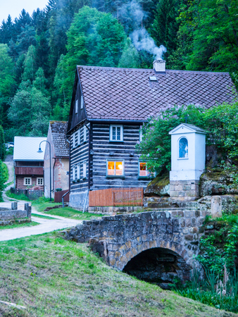 Old traditional timbered cottage with romantic with stone bridge at evening time. Czech rural architecture.の写真素材