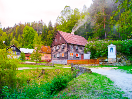 Old traditional timbered cottage with romantic with stone bridge at evening time. Czech rural architecture.の写真素材