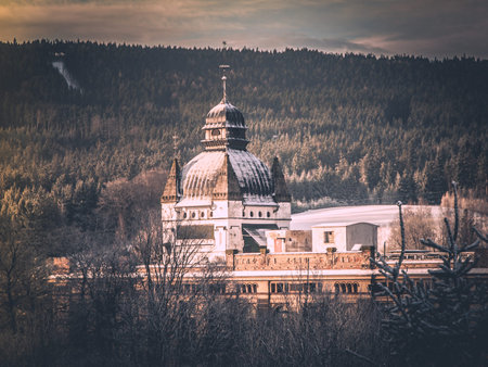 Old mountain factory with ornamental dome in winter landscape. Vintage style image.