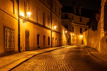 Narrow cobbled street in old medieval town with illuminated houses by vintage street lamps, Novy svet, Prague, Czech Republic. Night shot.の写真素材