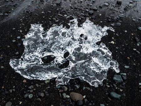 Piece of ice on black sand, natural detail, Iceland.