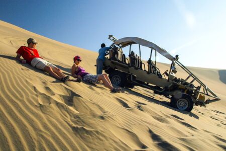ICA, PERU - JULY 6, 2010: Sand dune buggy parked on a dune and group of people having fun. Ica, Peru.のeditorial素材