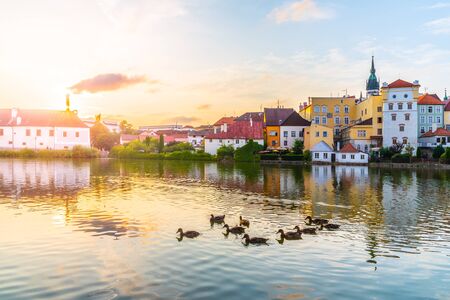 Jindrichuv Hradec cityscape at sunset time reflected in the Little Vajgar pond with flock of ducks, Czech Republic.の写真素材