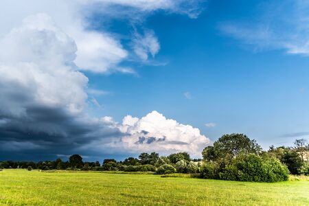 Before summer storm. Dramatic clouds coming in green and sunny landscape.の写真素材