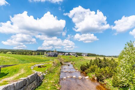 Sunny summer day in Jizerka mountain village. Jizerka river, green meadows and blue sky with white clouds, Jizera Mountains, Czech Republic.の写真素材