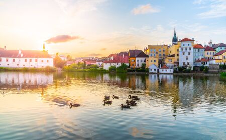 Jindrichuv Hradec cityscape at sunset time reflected in the Little Vajgar pond with flock of ducks, Czech Republic.の写真素材