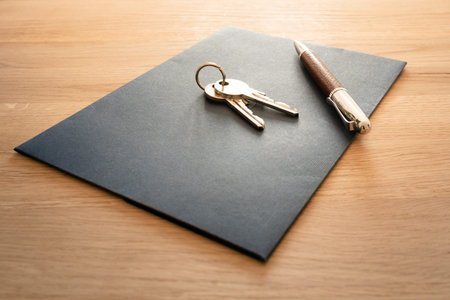 Keys, pen and envelope on the wooden table. Selling or rental of flat, house or another real estate...