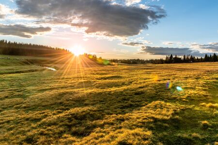 Rural grassland landscape in sunny spring evening. Sunset in Jizerka village with Jizerka river, Jizera Mountains, Czech Republic.の写真素材