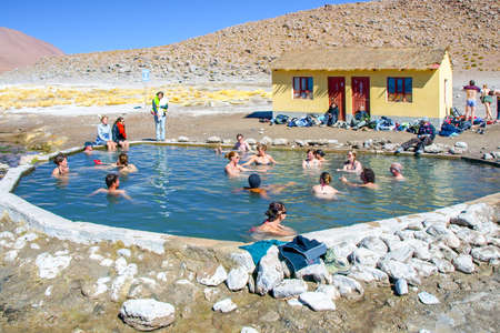 Hot springs Aguas Termales de Polques with pool of natural thermal water scenically set in impressive rocky Andean landscape, clouds of steam to flush with water of a lagoon in Bolivia, near the Chileのeditorial素材