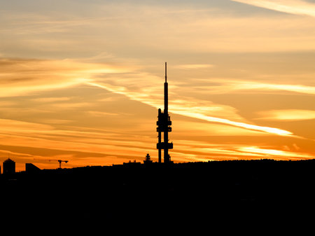 Silhouette of Zizkov Television Tower on the contrast with bright and vibrant orange morning sky. Prague, Czech Republicの写真素材